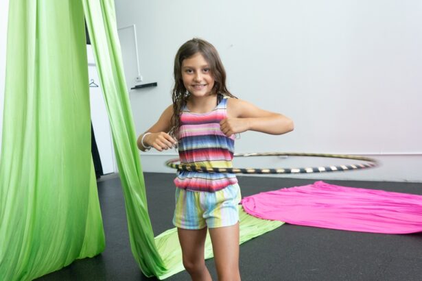 A young child with two thumbs up while standing in a hoop at camp