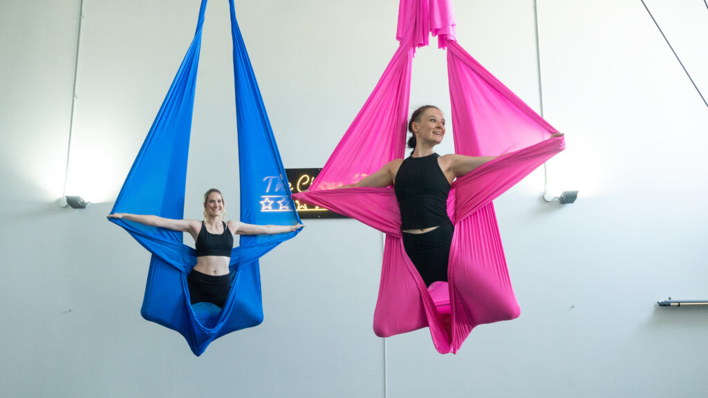 2 women in the air in pink and blue hammocks at The Circus Fix