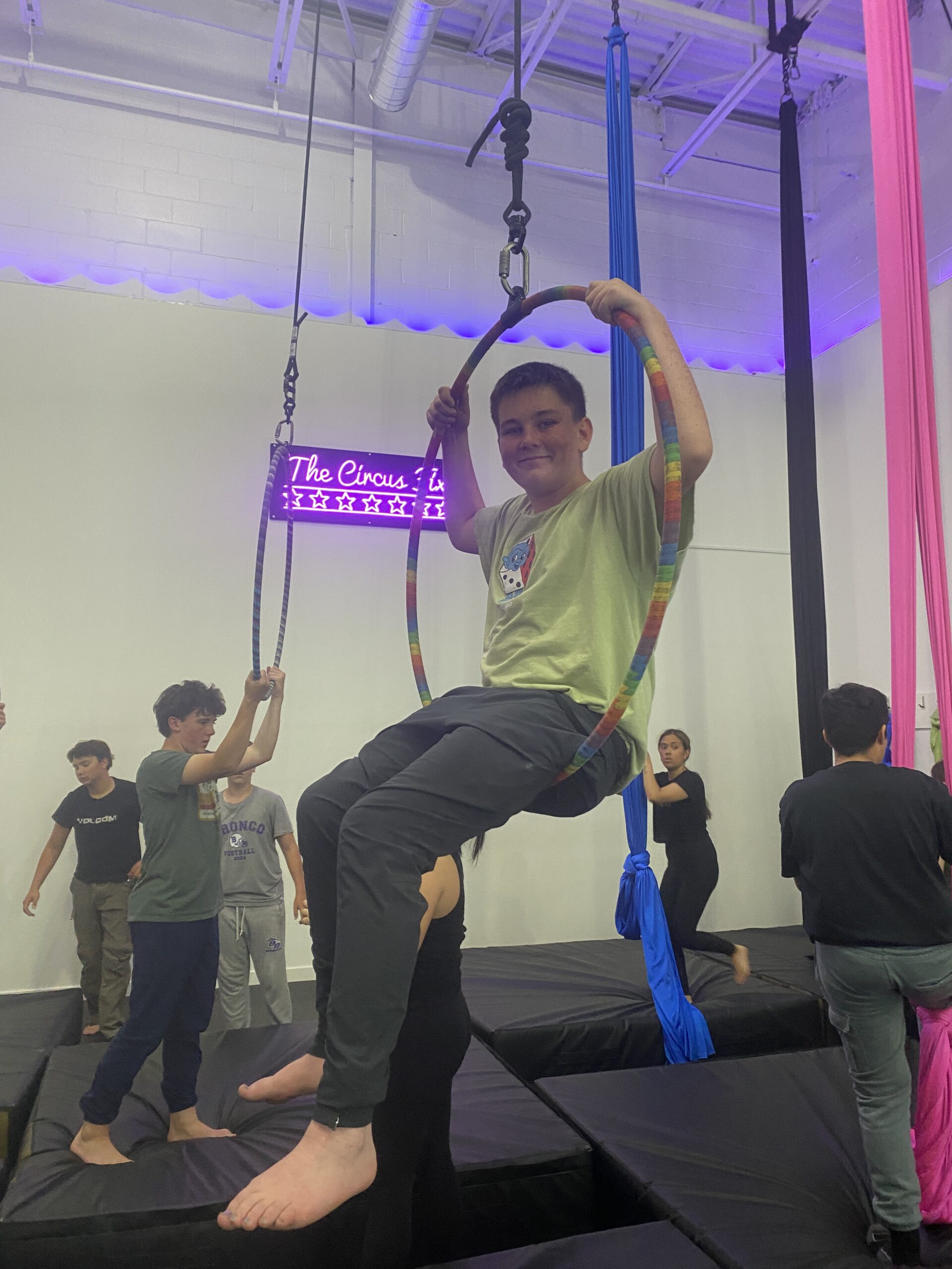 A teen boy sitting in a hoop.