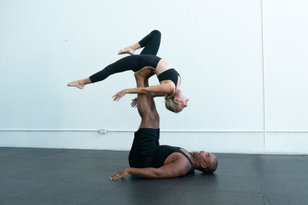 A man and woman doing partner acro. The man is on the floor with his legs in the air holding a woman in a back bend.