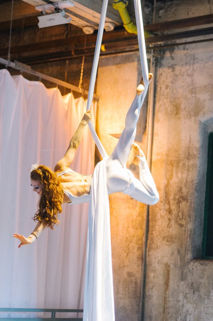 A woman all in white performing on white silks.