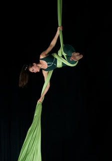 Photo of a woman in the air on green silks.