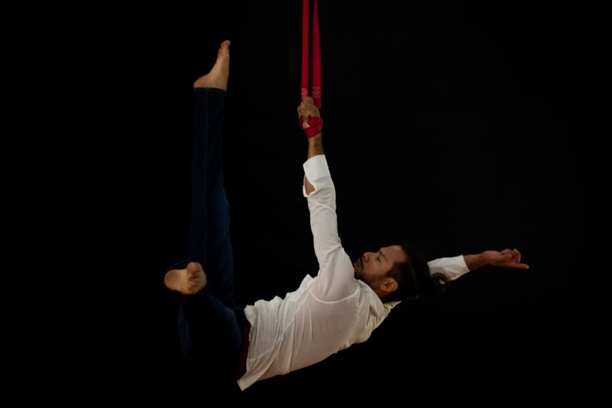 Picture of a man hanging from one arm in the straps